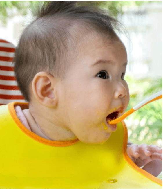 A baby eating a spoonful of food