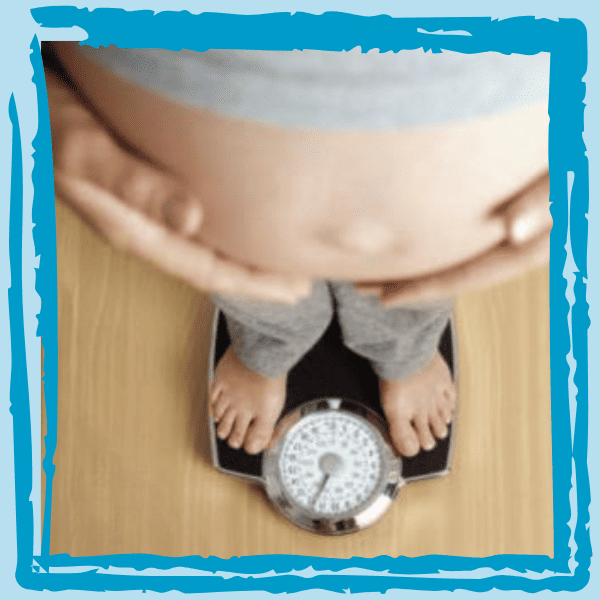 A pregnant woman weighing herself on a scale