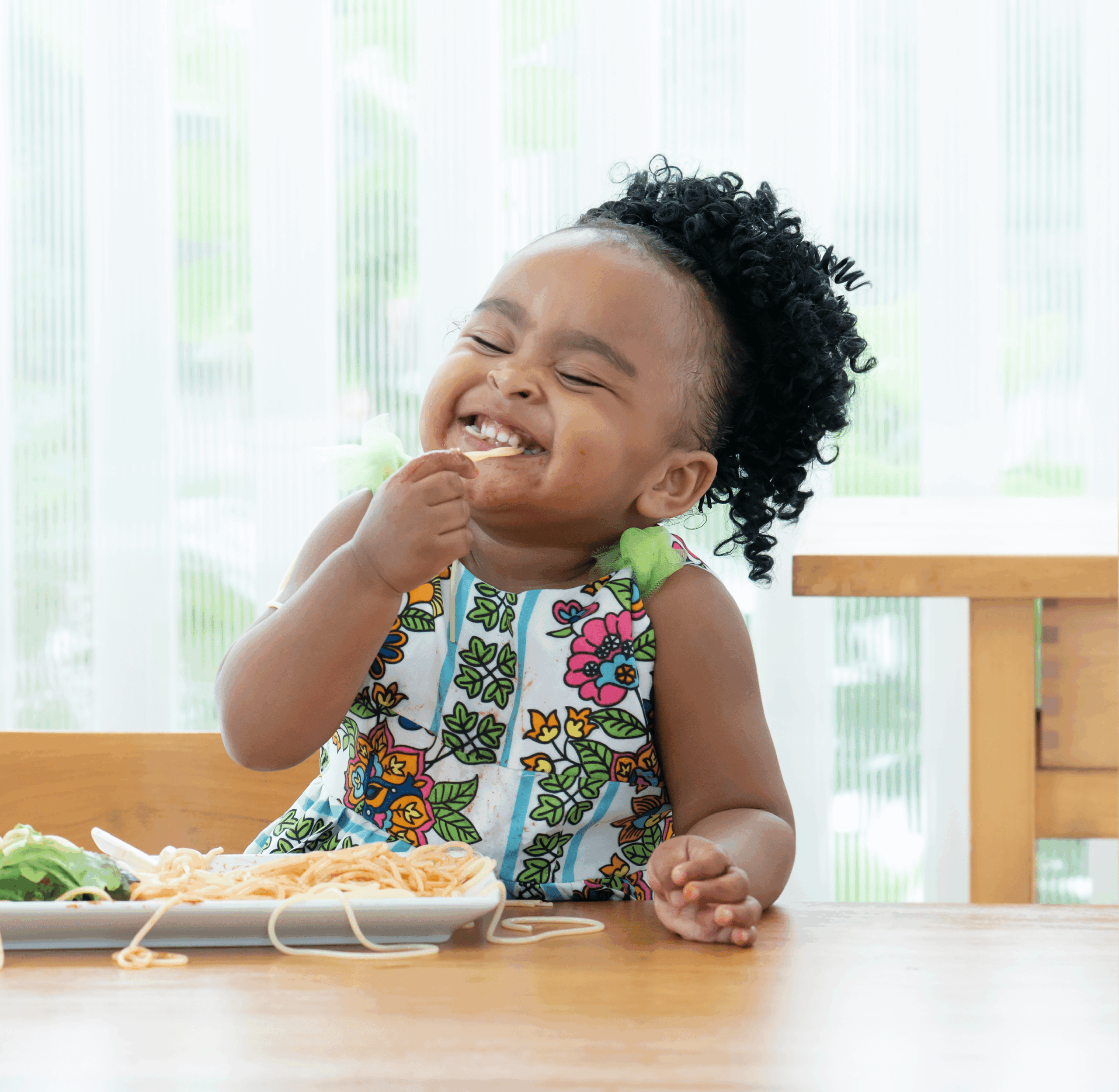 Girl eating spaghetti and smiling.