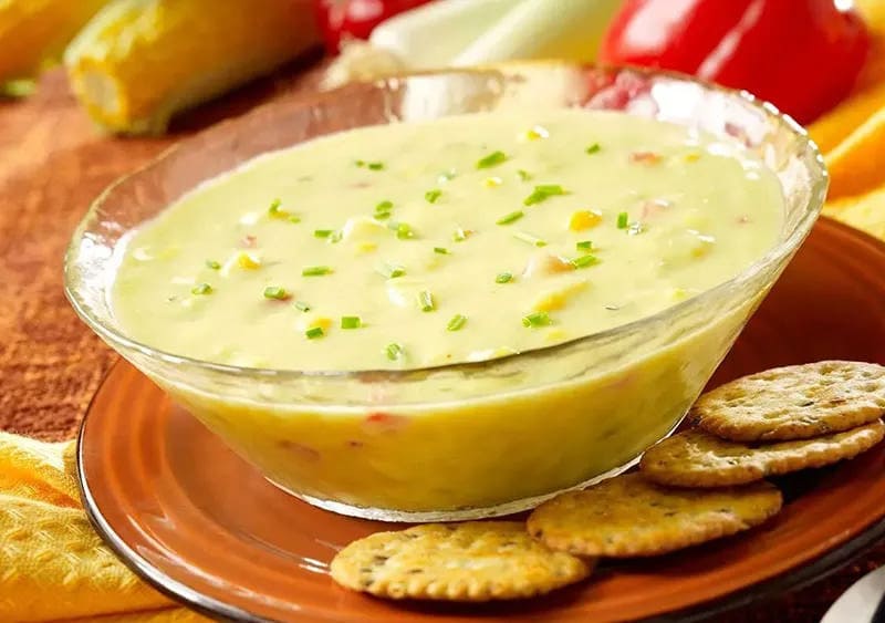 Corn chowder in a bowl with crackers on the side