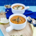 Creamy Butternut Squash and Apple Soup in a bowl with a lemon slice on the side.