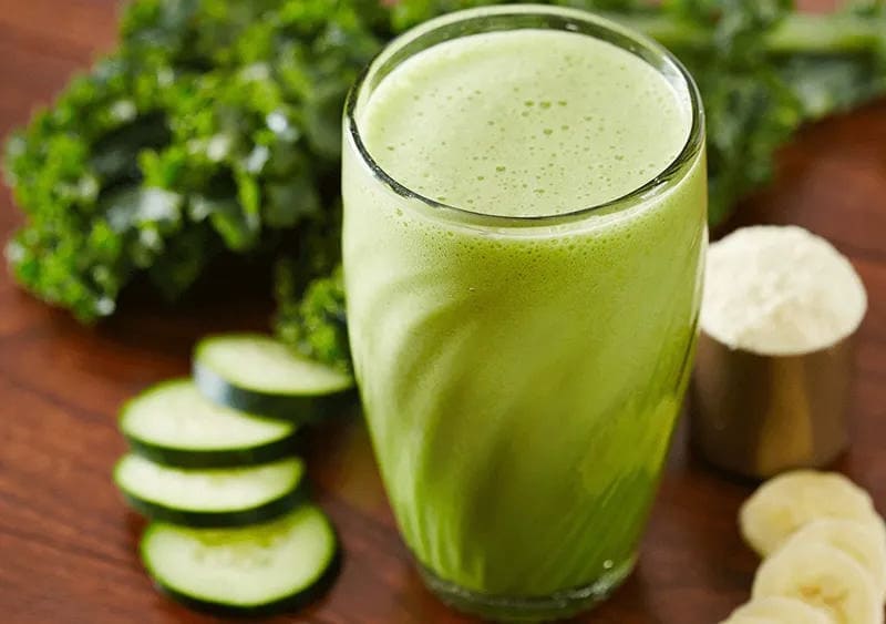 Green Power Protein Smoothie in a glass with cucumbers on the side