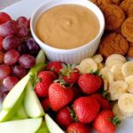 Pumpkin dip in a bowl surrounded by fruits and vegetables