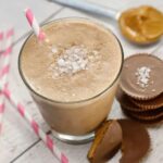 Salted Peanut Butter Cup Smoothie in a glass with peanut butter cups on the side