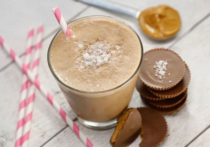 Salted Peanut Butter Cup Smoothie in a glass with peanut butter cups on the side