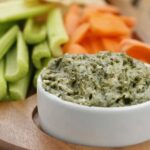 Spinach Artichoke Dip with celery and carrots in a bowl