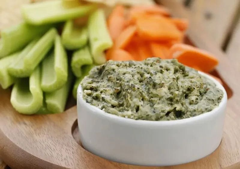 Spinach Artichoke Dip with celery and carrots in a bowl