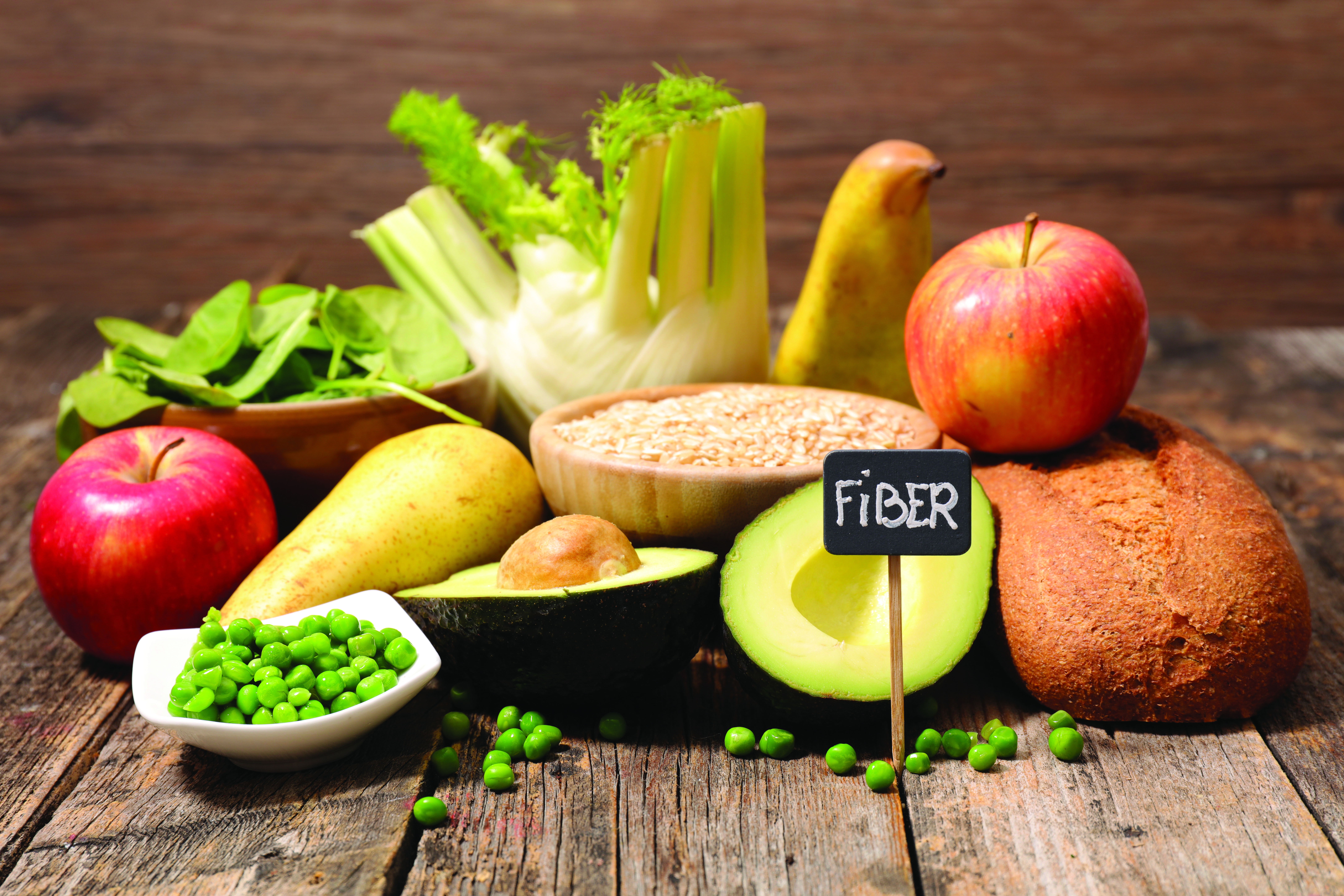 Multiple fruits, vegetables and grains on a table with a small sign that says 